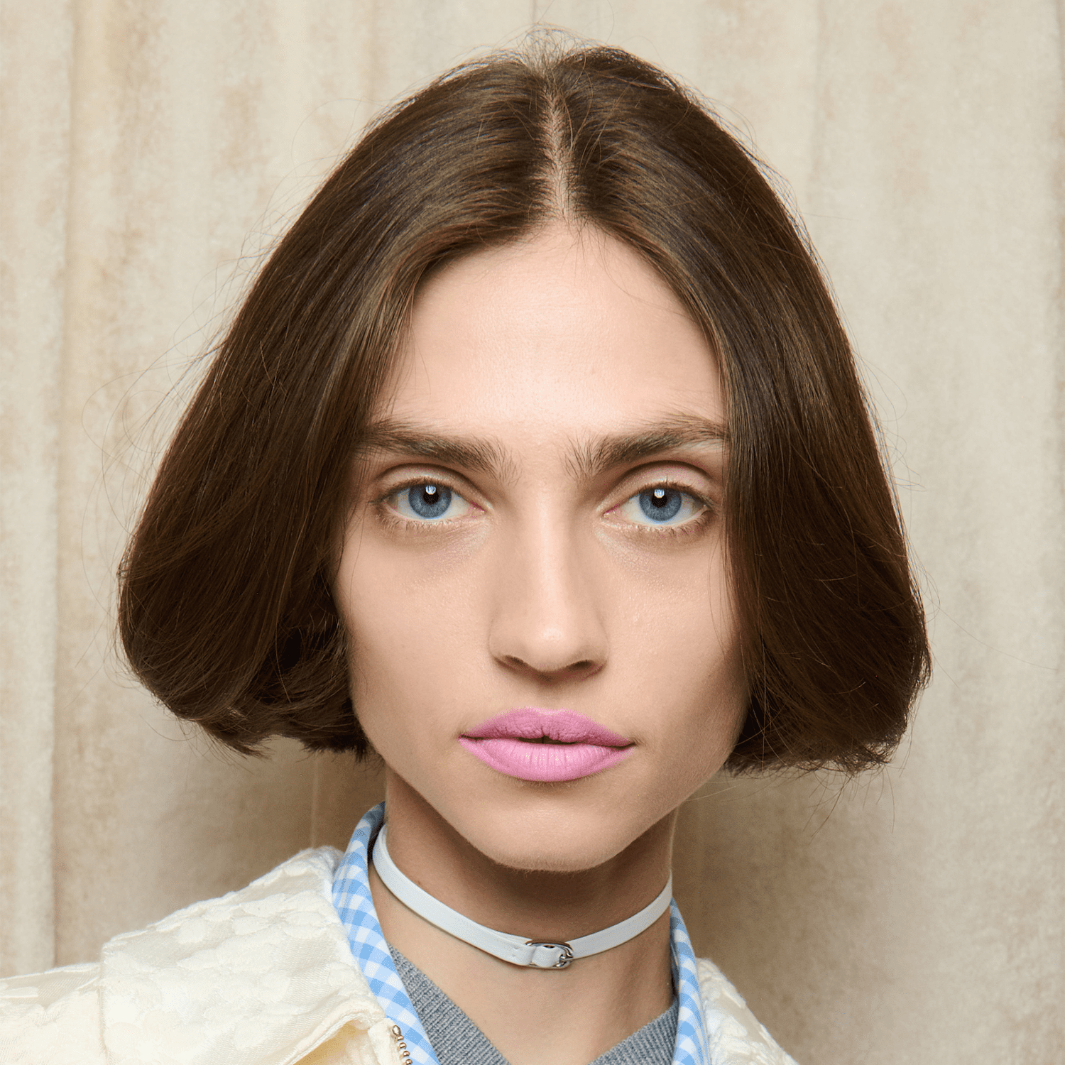 Model with blunt brunette bob and light pink lipstick